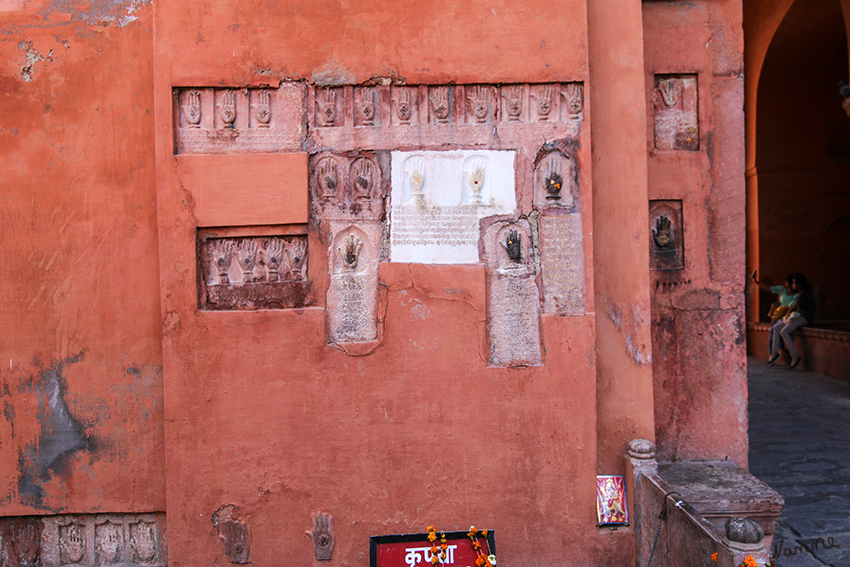 Bikaner - Junagarh-Fort
Die Handabdrücke stammen von den Witwen des Maharadschas die in den damals üblichen Verbrennungstod gingen, als sein Leichnam verbrannt wurde. Diese Art Freitod wird Sati genannt, die Frauen verschenkten auf dem letzten Weg durch die Stadt all ihr Hab und Gut an die Armen und warfen sich bei der Verbrennung des Leichnams mit auf den Scheiterhaufen. Frauen, die Sati begingen, wurden im Anschluss in hohen Ehren gehalten und teilweise göttlich verehrt.
Unter jedem Handabdruck steht der Name der Frau. 
Schlüsselwörter: Indien, Bikaner, Juangarh-Fort