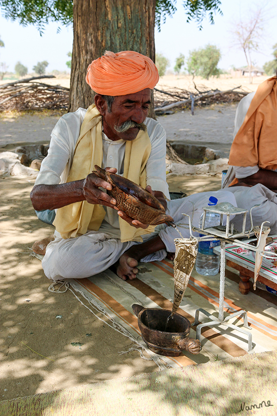 Manvar - Opium-Zeremonie
Es ist ein strohhalmdünner Strahl kochenden Wassers, den er aus einer Schale sorgfältig in das Stoffsieb lenkt, das über dem Boden hängt an einem wackligen Gestell, dampfend, hellbraun, vollgesogen wie ein großer Teebeutel. Es ist Zeit für "Amale", die Opium-Zeremonie zu Ehren Jambheshwars.
Jambheshwar der hinduistische Guru und leidenschaftliche Tierfreund, der Mitte des 16. Jahrhunderts durch Rajasthan zog und für nichts weniger warb als die totale Harmonie mit der Natur.
Schlüsselwörter: Indien, Manvar, Opium, Zeremonie