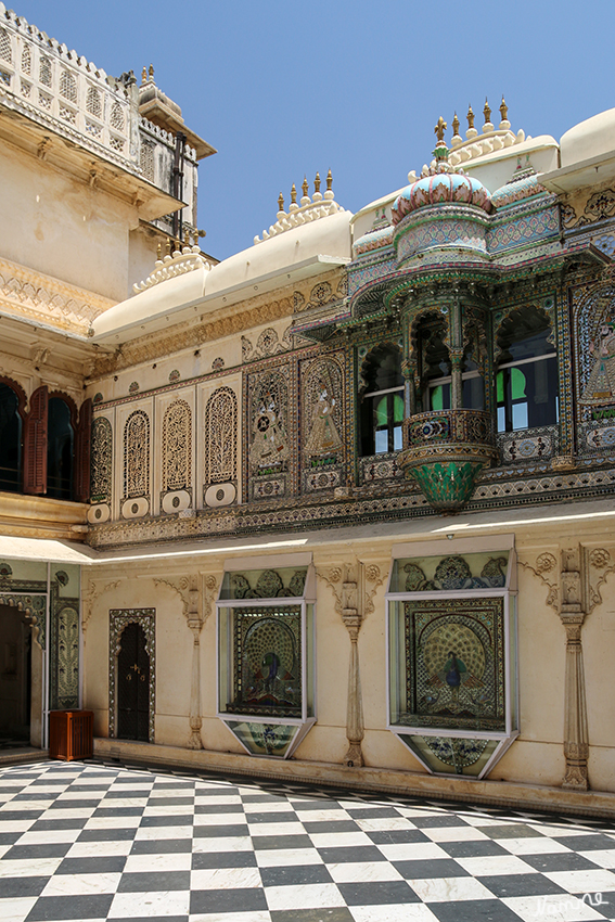 Udaipur - Stadtpalast
Der äußerst prächtige Mor Chowk (Pfauenhof) für die öffentlichen Audienzen. Die verschwenderische Dekoration an der Ostwand ist besonders auffällig. Der Hof entstand im 17. jahrhundert, diese Verzierungen wurden aber erst Ende des 19. Jahrhunderts im Rahmen einer grundlegenden Umgestaltung geschaffen. Pfauendarstellungen in Glaseinlegetechnik glitzern hier im Sonnenlicht.

Schlüsselwörter: Indien, Udaipur, Stadtpalast