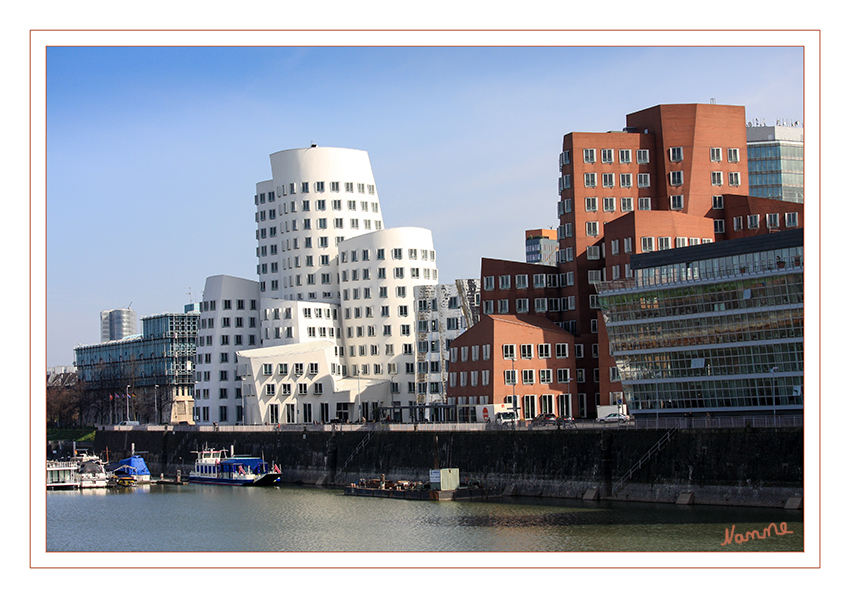 Hafenansicht
mit den Gehry-Bauten
Diese Türme sind krumm; sie sind schief, sie sind verwinkelt und verschachtelt. Sie sind eigentlich unmöglich und prägen in ihrer unmöglichen Realität das Bild des neuen Düsseldorfer Hafens: Die drei von Frank O. Gehry geschaffenen Gebäude am Hafenbecken, aus denen der "Neue Zollhof" besteht, bilden ein eigenartiges Ensemble lt.city-tourist.de
Schlüsselwörter: Düsseldorf; Medienhafen; Neuer Zollhof;