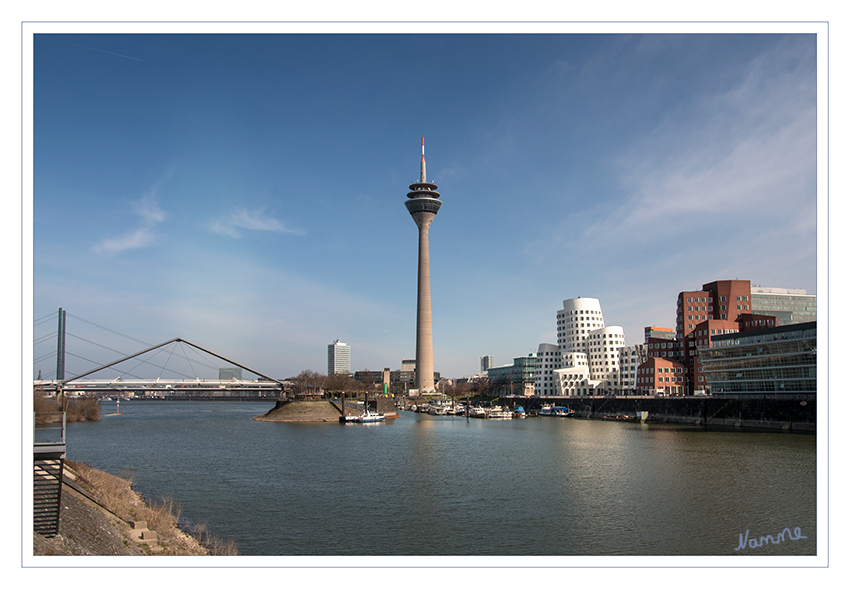 Medienhafen mit Blick 
links auf die Hafenbrücke Düsseldorf, sie ist eine Fußgängerbrücke und Hängesprengwerkbrücke, erbaut von 1989 bis 1992. Mittig der Rheinturm und rechts der östliche Medienhafen mit den Gehrybauten.
Schlüsselwörter: Düsseldorf; Medienhafen;