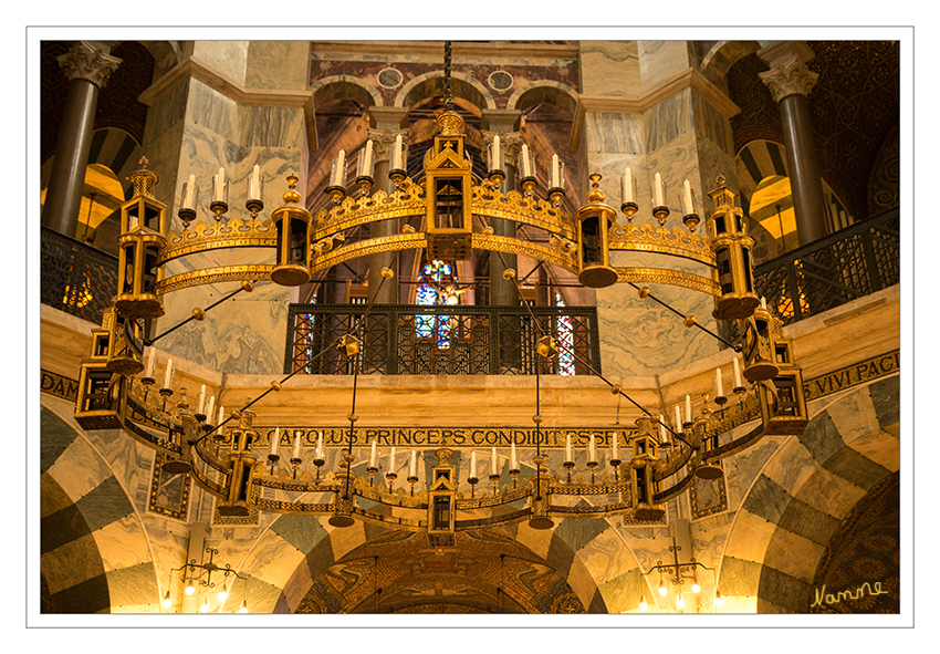 Aachener Dom
Der Barbarossaleuchter, ein Radleuchter von 4,16 Metern Durchmesser, hängt etwa vier Meter über dem Boden von der Kuppel des Oktogons herab. Die Form orientiert sich an der Geometrie des Bauwerkes und weicht damit von den im Mittelalter üblichen, auf der Zahl zwölf basierenden Radleuchtern ab. Datiert wurde der Leuchter auf die Zeitspanne um 1165 bis 1170. laut Wikipedia
Schlüsselwörter: Aachen, Dom