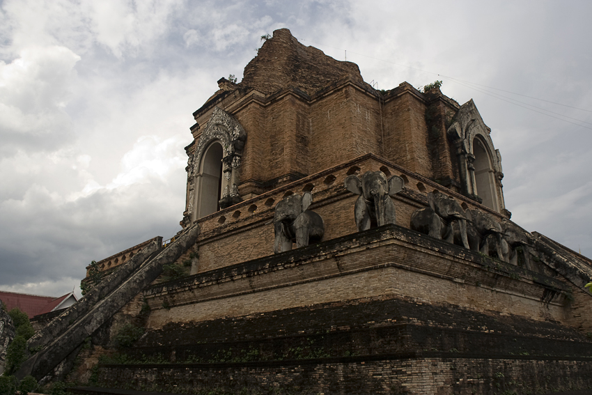Wat Chedi Luang
Im Jahre 1545, während der Regierungszeit von Königin Chiraprabha (15. Monarch in der Mengrai-Dynastie, 1545 - 1546), wurden Teile der Tempel-Anlagen durch ein Erdbeben und mächtiges Unwetter zerstört. Dieser Naturkatastrophe fiel auch der ehemals 80 Meter hohe Phra Dhatu Chedi Luang zum Opfer.
Schlüsselwörter: Thailand