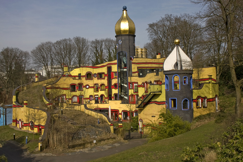 Hundertwasserhaus
Ein überraschender, fast märchenhafter Anblick bietet sich dem Besucher von der Brücke zwischen der Orangerie und dem Botanischen Garten: Ein goldenes Zwiebeltürmchen krönt das so genannte Hundertwasserhaus, das 2005 im Grugapark eröffnet wurde. Der Entwurf zu diesem fantasievollen bunten Haus war die letzte Arbeit des österreichischen Malers, Zeichners und Grafikers Friedensreich Hundertwasser (1928-2000).
Schlüsselwörter: Hundertwasserhaus