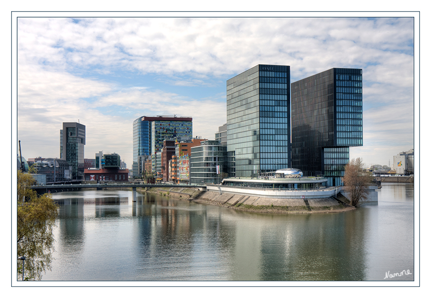 Medienhafen
Die von dem Architekturbüro JSK (Büro Düsseldorf) bereits im Jahr 2000 im Rahmen eines Bieterverfahrens zur Spitze der Speditionstraße entworfene Brücke hat eine Länge von 150 Metern und eine Breite von 11,60 Metern. Sie ist eine reine Fuß- und Radwegbrücke, die jedoch in Ausnahmefällen durch Rettungsfahrzeuge befahren werden kann. Rechts das Doppelhaus ist das berühmte Hyatthotel
Schlüsselwörter: Düsseldorf Medienhafen