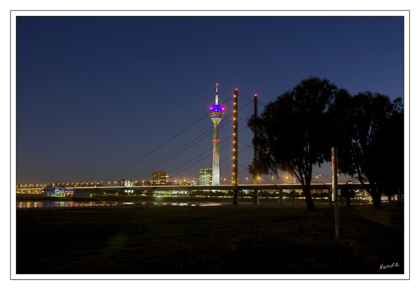 Rheinkniebrücke mit Fernsehturm (Rheinturm)
Weltweit einmalig ist die Funktion der leuchtenden Bullaugen des Rheinturms: 39 seiner 62 Bullaugen bilden, getrennt durch Flugsicherungsleuchten, in drei Höhenabschnitten über den 160 Meter langen Schaft des Turms eine "Dezimaluhr".
Schlüsselwörter: Rheinkniebrücke            Düsseldorf                 Rheinturm                Fernsehturm