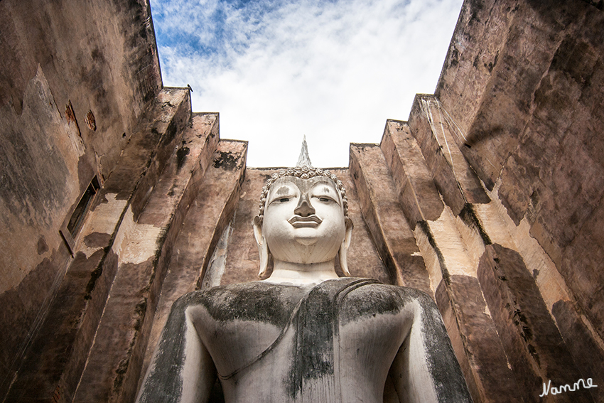 Wat Sri Chum
beeindruckt durch den riesigen Buddha genannt "Phra Achana" der seit dem 14. Jh. inmitten eines quadratischen Mondhop sitzt.
Mit etwa 15 m Höhe und einer Breite von Knie zu Knie mit 11,30 m ist er einer der größten sitzenden Buddhas des Landes.
Schlüsselwörter: Thailand Wat Sri Chum