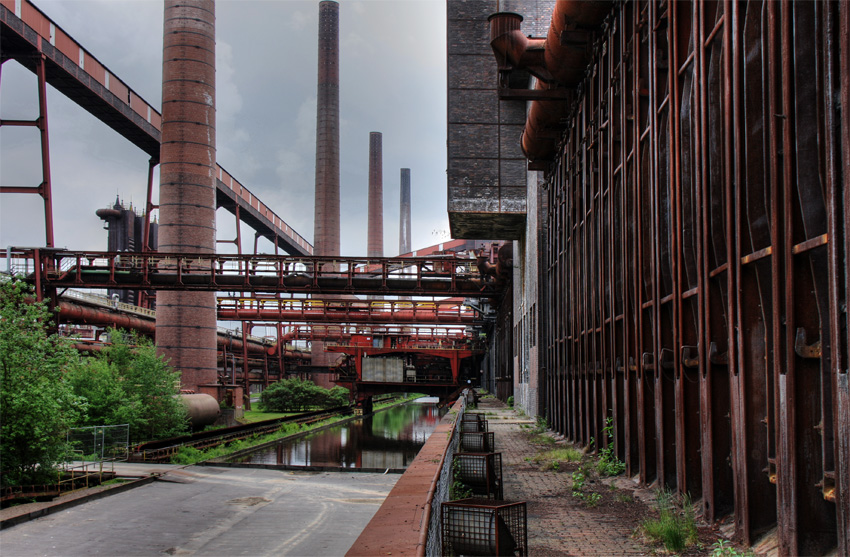 Kokerei Zollverein
von unten
Im Jahre 1964 verfügte die Kokerei über eine Kapazität von 5000 t Koks täglich. In den folgenden Jahren wurde die Zahl der Öfen von 192 auf 304 erweitert und die Leistung auf 8600 t Koks pro Tag erhöht. Sie beschäftigte zwischenzeitlich bis zu 1000 Menschen.
Schlüsselwörter: Kokerei Zollverein        Essen             Koksöfen