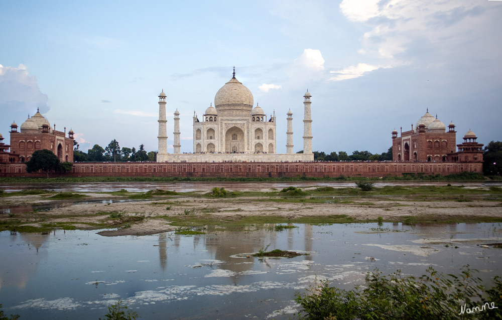 Taj Mahal von der Flussseite aus
Das Mausoleum am Ufer des Flusses wird rechts und links von zwei Gebäuden flankiert, die aus rotem Sandstein mit Verzierungen aus weißem Marmor bestehen; jedes dieser beiden Gebäude hat drei weiße Marmorkuppeln, niedriger als der zentrale Taj Mahal. Das Gebäude im Westen, in der Richtung von Mekka, ist eine Moschee. Das symmetrisch gegenüberliegende Gebäude im Osten des Mausoleums war ursprünglich ein Gästehaus mit gleichem Grundriss. lt Wikipedia
Schlüsselwörter: 2024