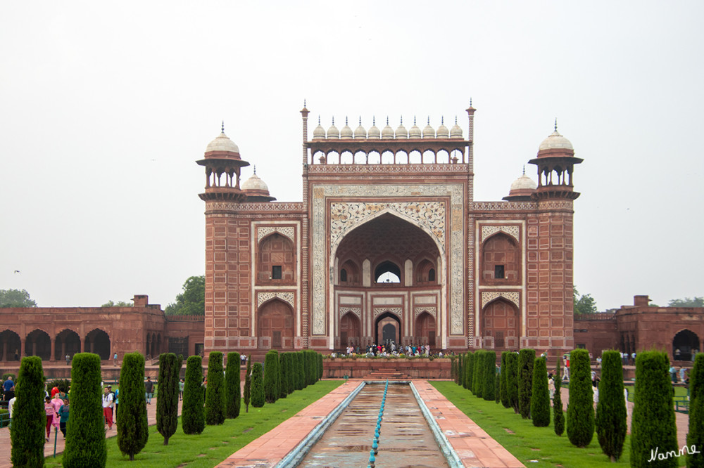 Taj Mahal
Das große Haupttor
Der Taj Mahal ist von einer Mauer aus rotem Sandstein umgeben. Ein Torbau aus rotem Sandstein ist mit weißen Marmor verziert. Die vier Ecken des Daches tragen kleine oktogonale, offene Kioske mit Kuppeln aus weißem Marmor; über dem äußeren und dem inneren Eingang je eine offene Passage, überwölbt von einer Reihe von je elf kleinen weißen Kuppeln. Es sind insgesamt 26 Kuppeln. Auch der Torbau ist mit Zitaten aus dem Koran verziert. lt Wikipedia
Schlüsselwörter: 2024