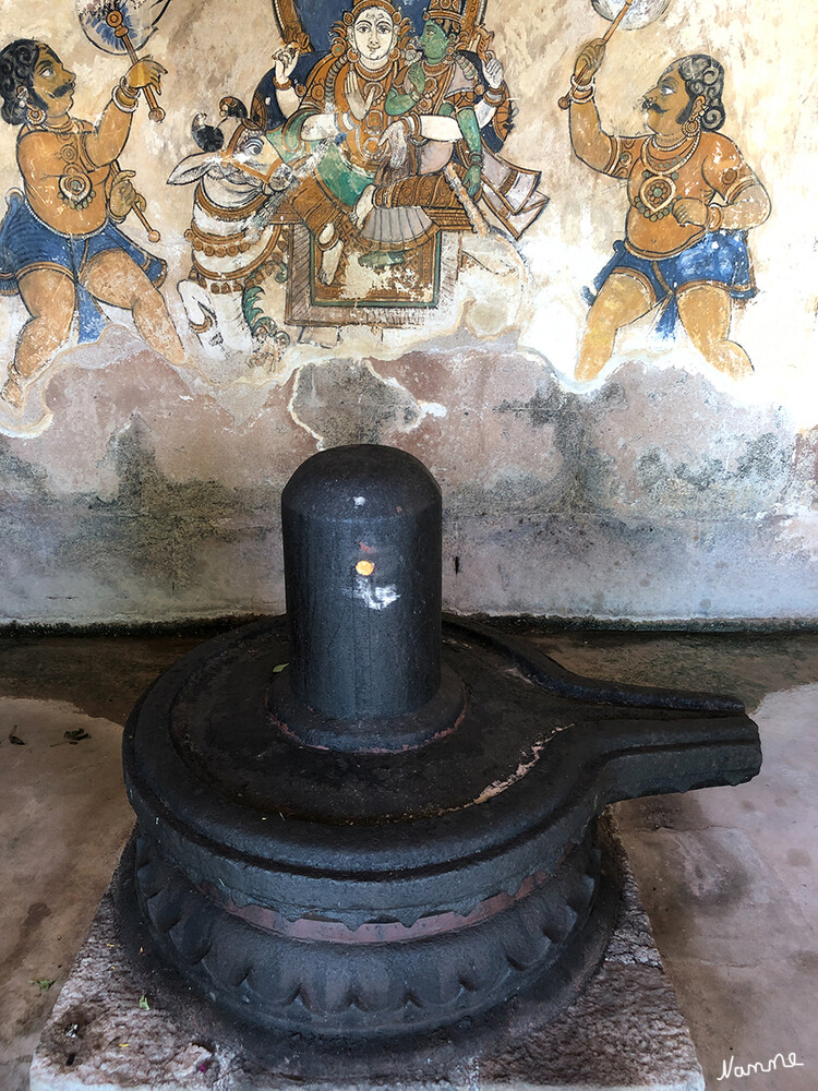 Brihadishvara-Tempel
Eine Reihe von Shiva Lingams mit alten Nayaka-Malereien an der inneren Mauer des nördlichen Gangs, Brihadishvara-Tempelkomplex. Die Arkaden um den Ardhamandapa (Korridor des Tempels) zeigen Frescos aus der Chola-Zeit. Sie wurden in der ersten Hälfte des letzen Jahrhunderts entdeckt und zeigen eine Vielzahl weltlicher Themen, unter anderem die Lehren des Saiviamus.
DIE KÜNSTLER VERWENDETEN PFLANZLICHE FARBSTOFFE, UM DIE WANDBILDER ZU MALEN.  lt.indienrundreisen
Schlüsselwörter: 2024