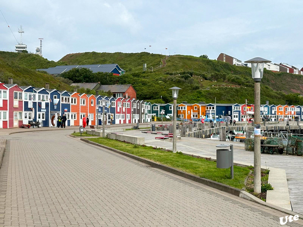 Die Hummerbuden
sind ehemalige Schuppen und Werkstätten der Fischer der Nordseeinsel Helgoland. Nach den Zerstörungen des Zweiten Weltkrieges und der Wiederbesiedelung Helgolands 1952 wurden die Hummerbuden vom Hamburger Architekten Georg Wellhausen entworfen. Die Farbgestaltung stammte von Johannes Ufer. lt.Wikipedia
Schlüsselwörter: 2025