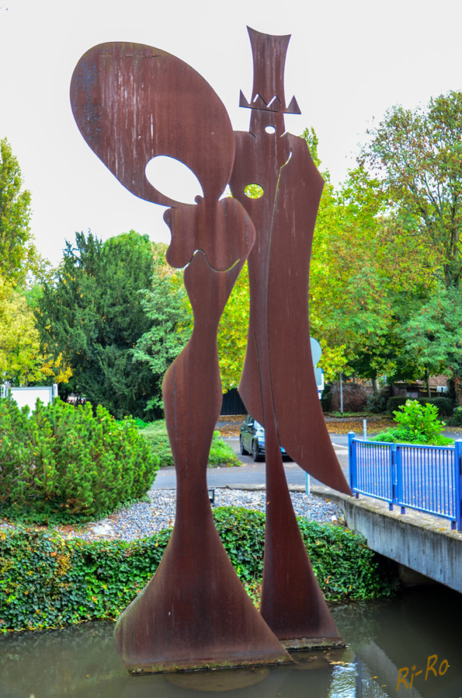 Schützenkönigspaar
gestaltet vom ehemaligen Landrat des Rhein-Kreises Neuss. Er ist auch als Künstler tätig. In Neuss u. Umgebung gibt es einige Kunstwerke im öffentlichen Raum, die Dieter Patt geschaffen hat. Die Stahlskulptur wurde 1997 aufgestellt, besteht aus 6 Teilen u. ist 8 m hoch. Für die Standfestigkeit im Graben sorgt eine eigens dafür entwickelte Betonplatte. (Kulturamt)
Schlüsselwörter: 2025