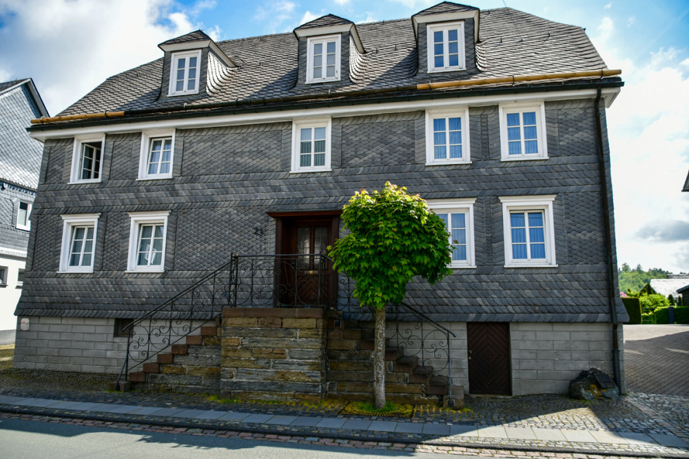 Bürgerhaus in Schmallenberg
aus der Zeit von 1823 bis 1825 mit ortstypischer Fassadenausbildung. Das Schmiedegitter der Freitreppe wurde neurokokohaft gestaltet. (Liste Baudenkmäler)
Schlüsselwörter: 2026